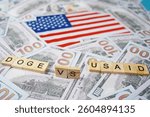 The inscription DOGE VS USAID on the background of the US flag and dollar bills.