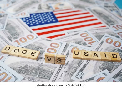 The inscription DOGE VS USAID on the background of the US flag and dollar bills.