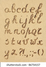 The inscription of handwritten alphabet letters on wet beach sand