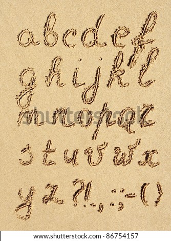 The inscription of handwritten alphabet letters on wet beach sand