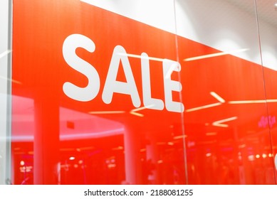 The Inscription In Large Letters SALE On A Red Background On A Shop Window. Discount Announcement Banner, Holiday Sale, Black Friday Concept.