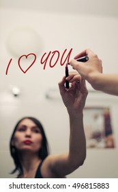 Inscription I LOVE YOU by lipstick on mirror and reflection of a girl