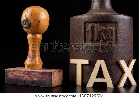 Inscription tax and old weight 1 kilogram. Stamp and store accessories on a dark table. Black background.