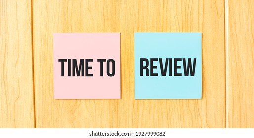 Inscription TIME TO REVIEW On Pink And Blue Square Sticky Sticker On Wooden Wall