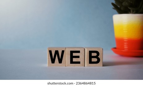 The inscription WEB on wooden cubes isolated on a blue background, the concept of business and finance. - Shutterstock ID 2364864815