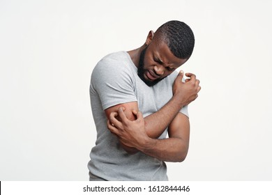 Insect bite allergy. Young afro man scratching his itching hand, white background, copy space