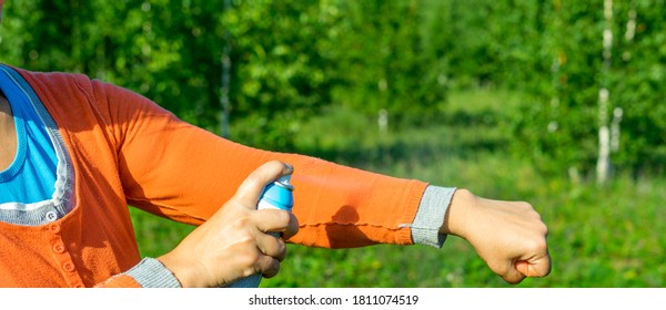 Insect repellent applying on caucasian women hand. Woman spraying mosquito repellent on hand. Skin protection against tick and other insect. Close-up view. Summer and autumn concept of self protection