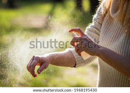 Insect repellent. Woman tourist applying mosquito repellent on hand during hike in nature. Skin protection against tick and mosquito bite