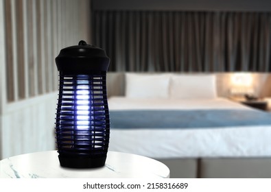 an insects mosquito electric blue light killer lamp is put on the white marble table in the nice bedroom with curtain background to protect the mosquito during sleeping time - Shutterstock ID 2158316689