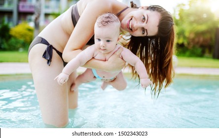 Insecure Caucasian 6 Months Old Baby Boy Learning How To Swim At Swimming Pool. Mother Holding Her Son. First Time At Pool Concept.