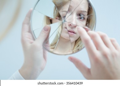 Insecure pretty young woman holding broken mirror - Shutterstock ID 356410439