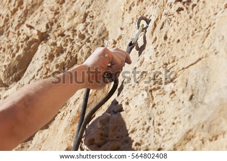 Insert the rope in the quickdraw with one hand climber on mountain terrain