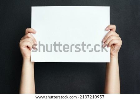 Insert your message here. Studio shot of an unrecognisable woman holding a blank board against a black background.