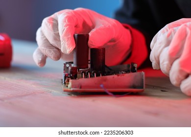 inserting a capacitor into a printed circuit board by a person on a blue background