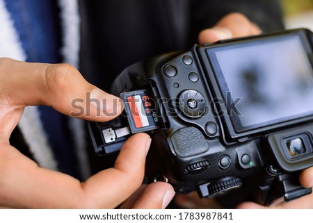 Inserting high-capacity memory card into photo camera outdoors