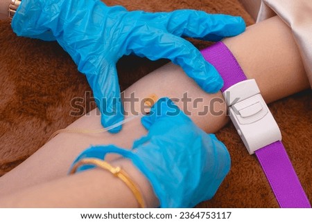 Inserting an intravenous needle and cannula into a patients arm. Glutathione IV infusion therapy session at an aesthetic clinic.