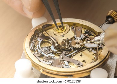 Inserting parts. Cropped close up of a watch craftsman putting a cogwheel into mechanical watch he is repairing professionalism carefulness delicate work hands details fixing instruments concept - Powered by Shutterstock