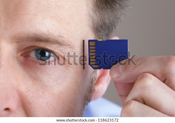 Inserting SD memory card into\
slot in human head concept for memory upgrade, forgetfulness or\
computing
