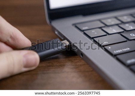 inserting usb flash drive into laptop port for data transfer and storage on wooden surface