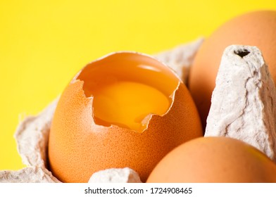 Inshell egg yolk close-up macro. Chicken eggs in tray on a yellow background