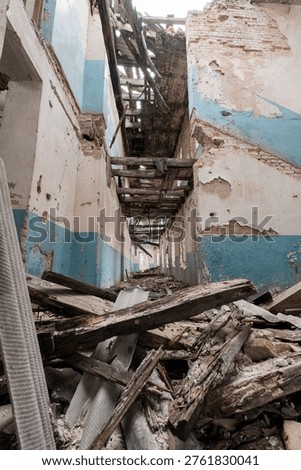 Inside an abandoned structure showcasing crumbling walls, scattered wood debris, faded blue paint, and collapsed ceiling beams highlighting urban decay and neglect