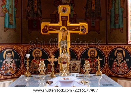 Inside the altar of an orthodox church, with traditional artifacts and the richly decorated cross and walls.