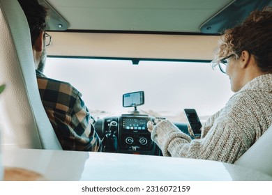 Inside back view of vehicle cabin like motorhome and couple traveling and using gps navigation system and phone to plan road trip and destination. Concept of camper van vacation adventure tourism - Powered by Shutterstock