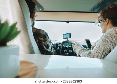 Inside back view of vehicle cabin like motorhome and couple traveling and using gps navigation system and phone to plan road trip and destination. Concept of camper van vacation adventure tourism - Powered by Shutterstock