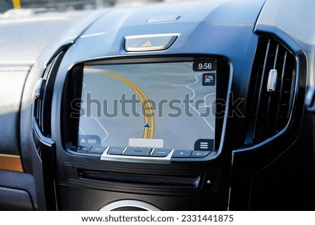 Inside a Brand new hatchback car from the factory with the central display monitor showing the GPS Sat Nav with passenger airbag lights on and media buttons and knobs. Hazard light button with Screen
