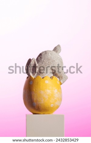Inside the bright yellow Easter egg, a plush rabbit nestles comfortably, creating a whimsical still life. An Easter card