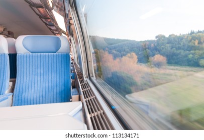 Inside Cabin Of Modern Express Train. Nobody In Blue Chairs At Window. Motion Blur. Comfortable Chairs And Table In Foreground, Nature Outside Window. Travel, France, Europe.