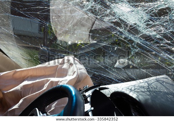 Inside the car, sunny, with airbags and\
windshield cracks due to accident\
damage.