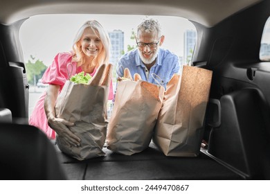 Inside the car trunk view of a cheerful senior couple checking groceries, representing a happy retired life - Powered by Shutterstock