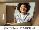 Inside of cardbox bottom view. African girl unpacking delivery looking in box. Woman opening carton box. Female getting parcel looking at delivered goods items. Satisfied client positive feedback