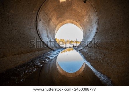 Inside a circular concrete drainage culvert with a trickle of water