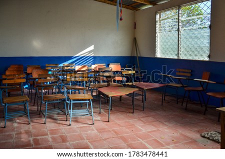 Inside a classroom with chairs and desks in a public school class in Nicaragua. Room and equipment in poor condition. Wood chairs and tables no students. Concept for education in developing countries