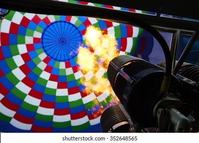 Inside of a colorful hot air balloon as it is inflated for flight, burning burner