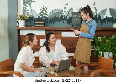 Inside cozy cafe, two customers laugh while engaging with Asian 
woman barista holding digital tablet, casual and friendly service moment captured, rustic decor in background. Small family business - Powered by Shutterstock