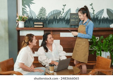 Inside cozy coffee, two customers laugh while engaging with Asian 
woman barista holding digital tablet, casual and friendly service moment captured, Small family business - Powered by Shutterstock