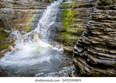 Inside the Devils Bathtub waterfall and pool as people slide in Spearfish Canyon, South Dakota