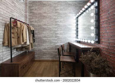 Inside the dressing room in vintage style brick pattern wallpaper wooden table and chairs With a clothes rail, a large mirror and LED lights for makeup and styling.