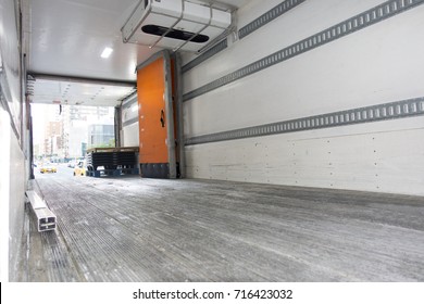 inside empty truck trader cargo with opened orange door parked on a new york city street with yellow cabs and other traffic