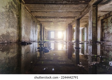 Inside flooded dirty abandoned ruined industrial building and water reflection 