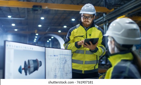 Inside the Heavy Industry Factory Female Industrial Engineer Works on Personal Computer She Designs 3D Engine Model, Her Male Colleague Talks with Her and Uses Tablet Computer. - Shutterstock ID 761907181