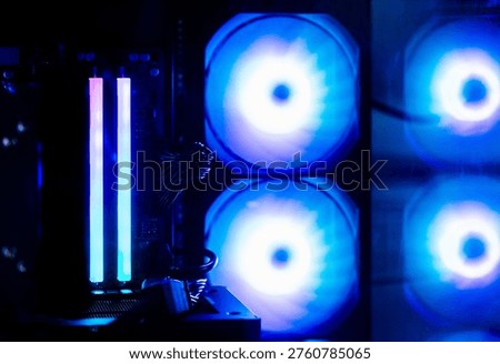 Inside a high-performance gaming PC: a close-up of RAM modules with customizable blue lighting and glowing cooling fans during an esports match.