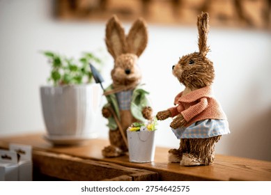 Inside, indoors, interior decor, decorating, decorations. Seasonal, spring season, Easter secular holiday. Anthropomorphic bunny rabbit figures, bunnies, rabbits. Planter, green plant. Counter, shelf. Garden, gardening. 