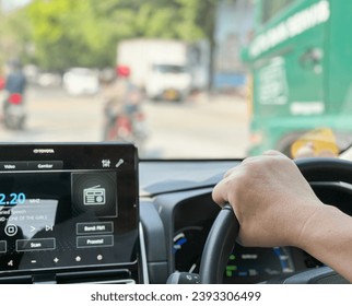 Inside interior of a car while driving with hand gripping the steering wheel.View of the street visible through front car window. bokeh or blurred background.