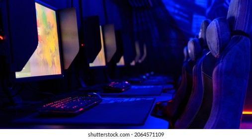 Inside Of Internet Cafe, Glow Blue Neon Light, Illuminated Cybercafe Room, Tables With Computers Empty Chairs In Row, No People. Modern Place For Gamers, Computer Game Compete, Fun, E-sport Concept