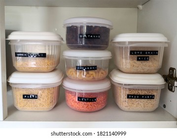 The Inside Of A Kitchen Cupboard Containing  Dry Food Organised In Transparent, Labeled Plastic Boxes.  Organised Pantry And Kitchen Concept.