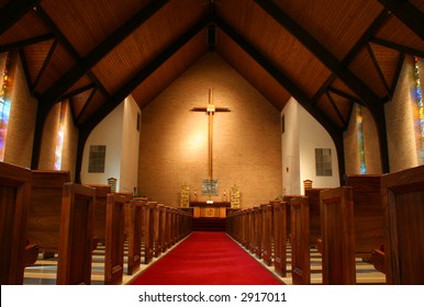 Inside Of A Large, Modern Church With Pews And Cross Visible